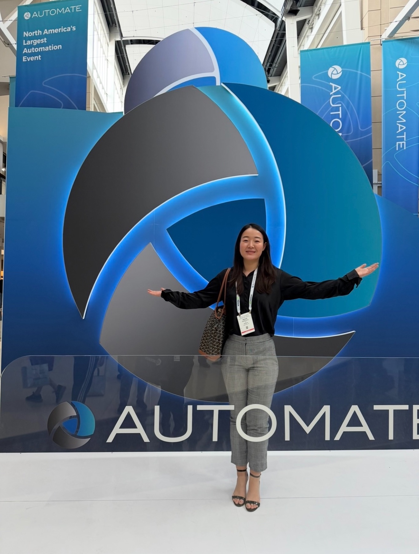 A Nyotta founder at the entrance to AUTOMATE, North America's largest automation event, arms open in front of the show's logo wall.