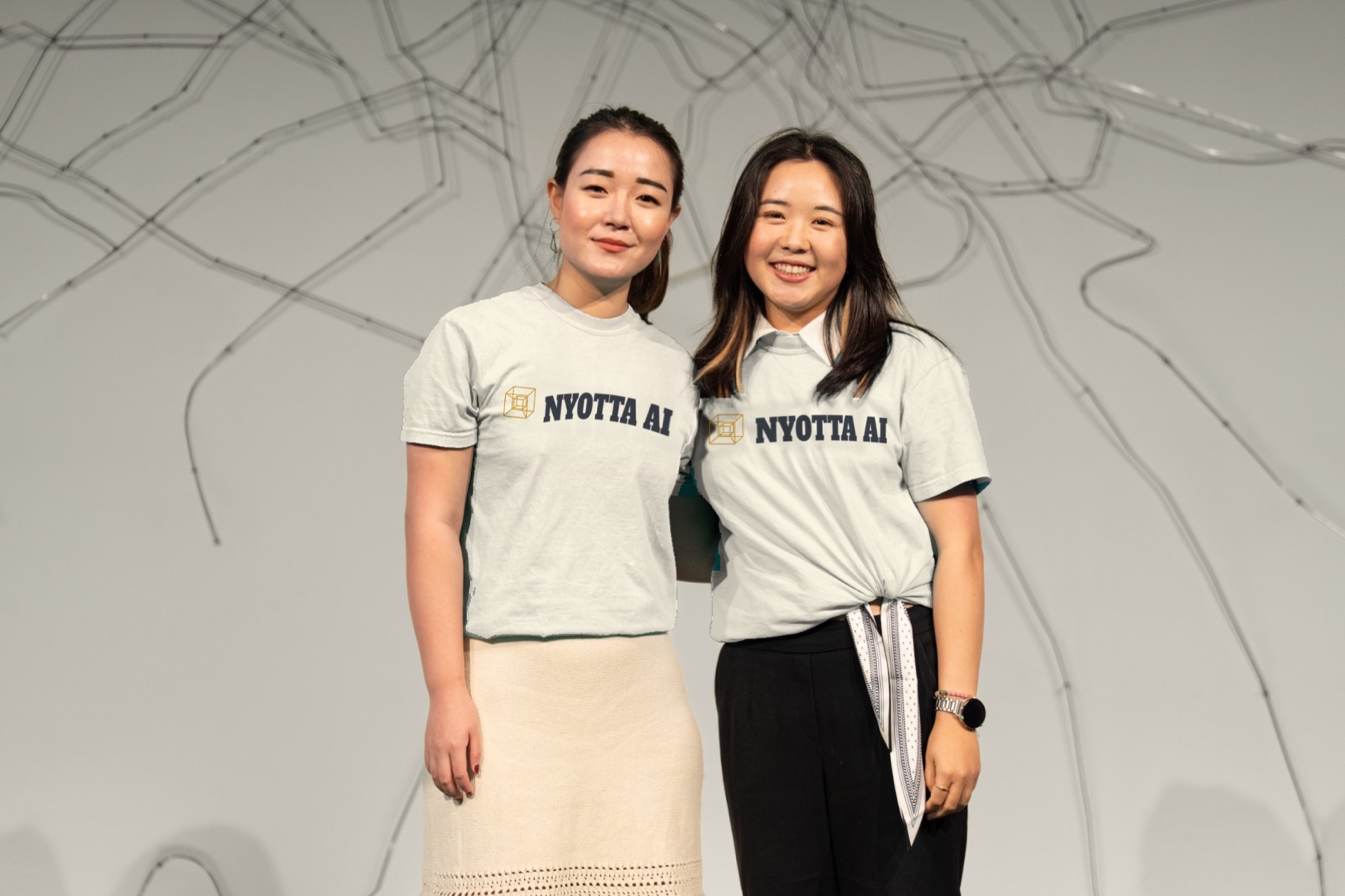 Nyotta's two founders on stage in Nyotta AI t-shirts.