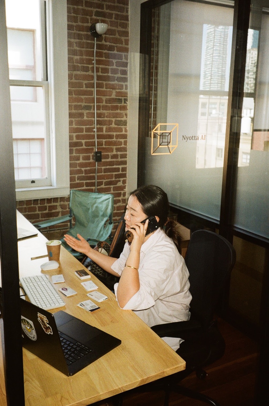 Working at a desk in the Nyotta office in San Francisco, the Nyotta mark etched on the glass partition behind.