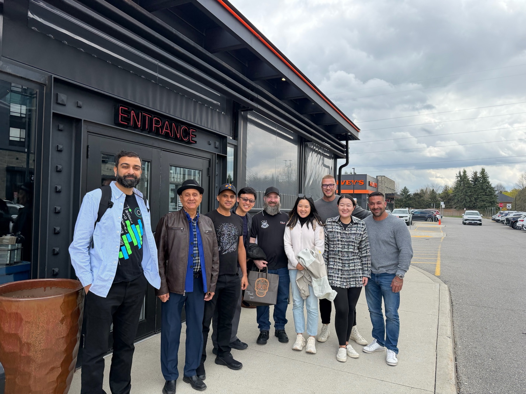A group of nine, the Nyotta team among them, outside a venue entrance on an overcast day.